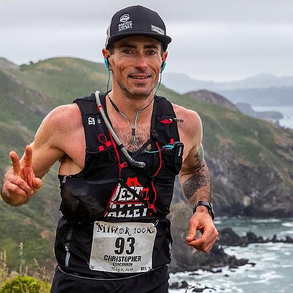 Chris smiles as he runs on a coastal trail