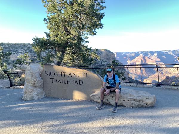 Chris sits next to the Bright Angel trailhead sign, exhausted after finishing.