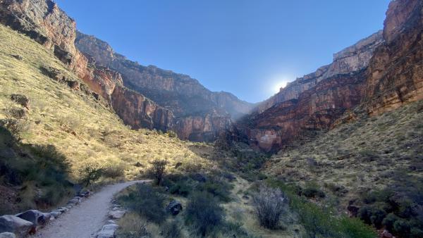 The sun disappears beyond the rim, leaving the trail shaded