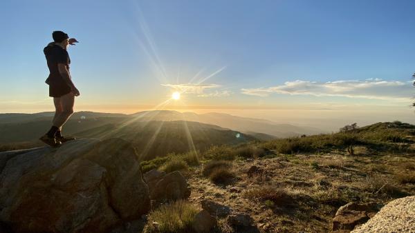 Chris, standing on the Palomar Mountain High Point, looks at the sun as it sets over the marine layer