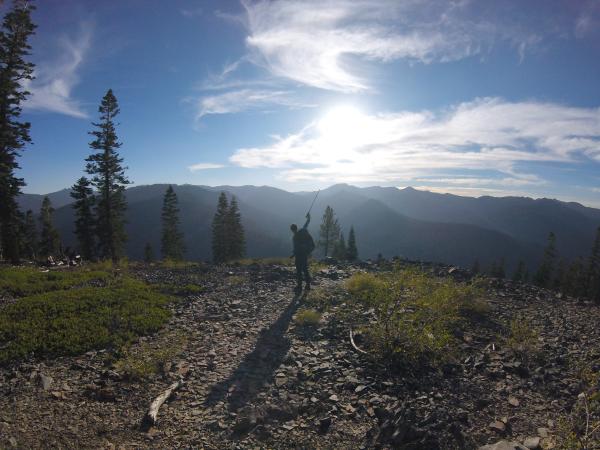 Chris raises a hiking pole, pointing it into the sunset