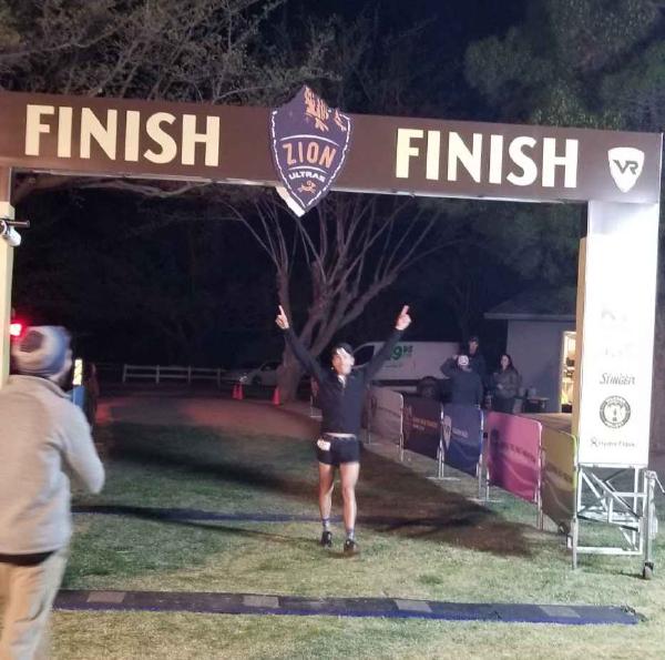 Chris runs across the finish line with his hands in the air